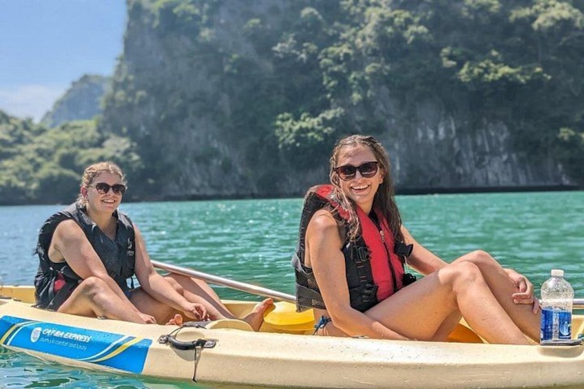 Dos personas en un kayak amarillo con chalecos salvavidas, rodeadas de agua tranquila y acantilados. 5
