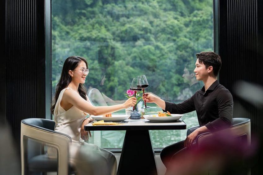 Una pareja cenando en una mesa con vistas a un paisaje boscoso a través de amplios ventanales. 4