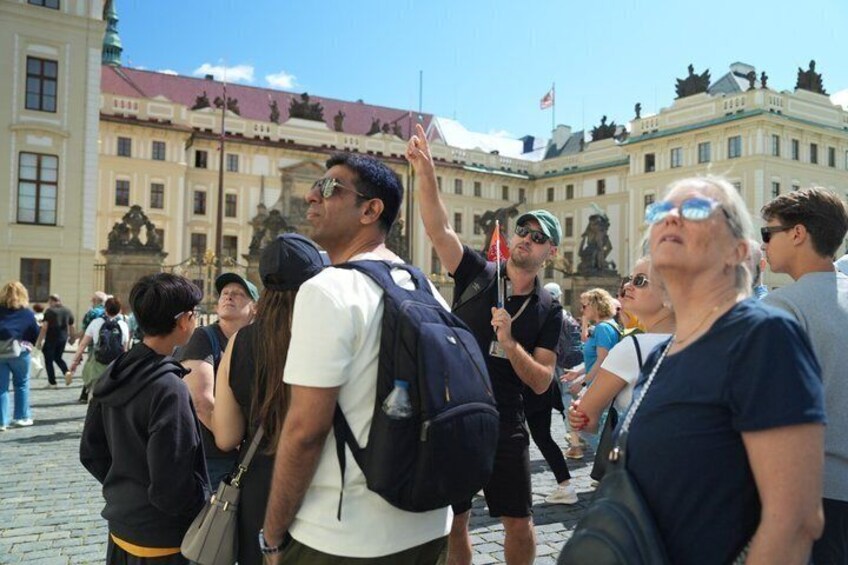 A group of tourists in a historic square with classical architecture and statues. 5