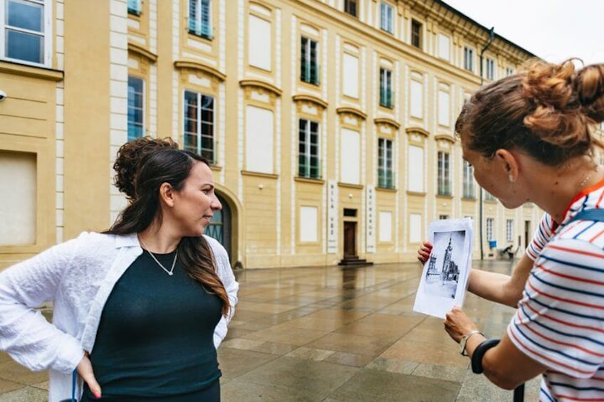 Two people conversing in an open courtyard with classical architecture. 5