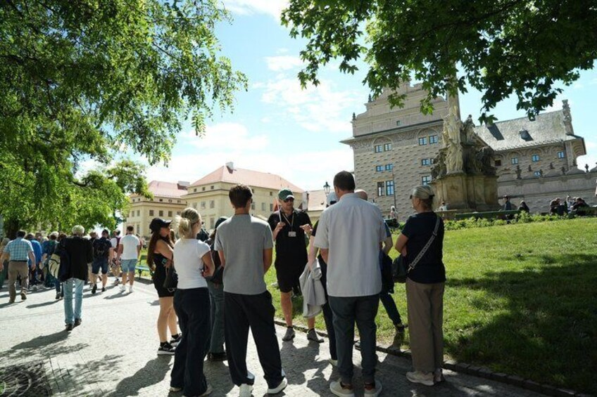 A group of people walking on a paved path in a park with a large building in the background. 4
