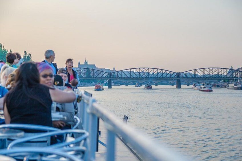 A river with a bridge, people on the riverbank, and boats on the water. 3