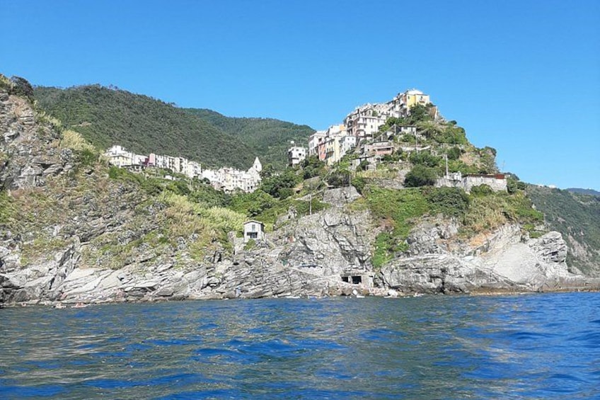Un pueblo costero con edificaciones en una ladera, costa rocosa y agua azul cristalina. 4