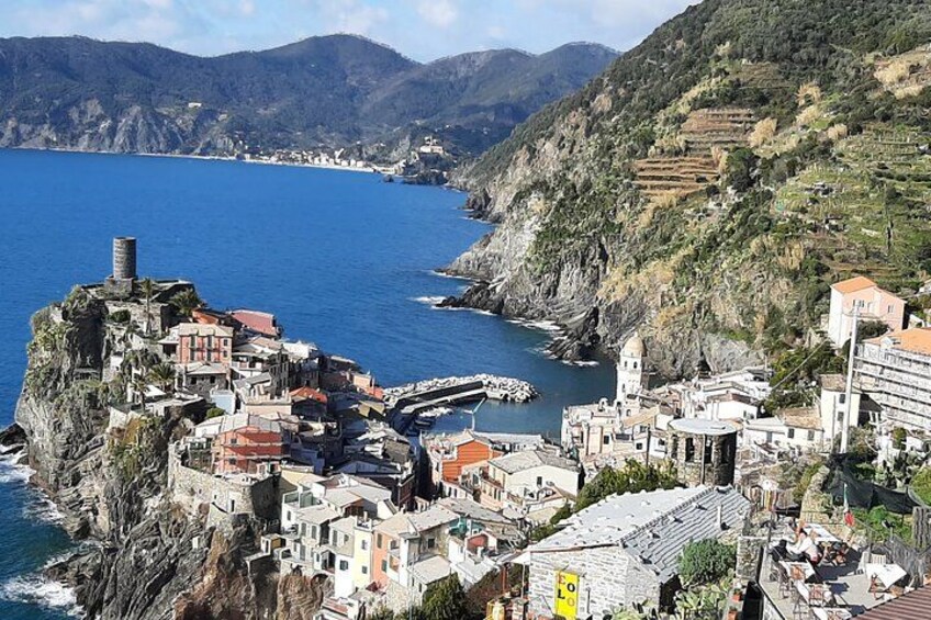 A coastal village with terraced houses, a lighthouse, and a rugged coastline. 3