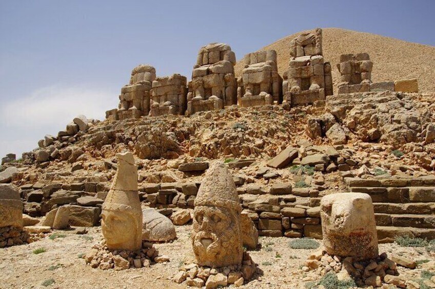Ancient stone ruins with large blocks and a pyramid-like structure in the background. 1