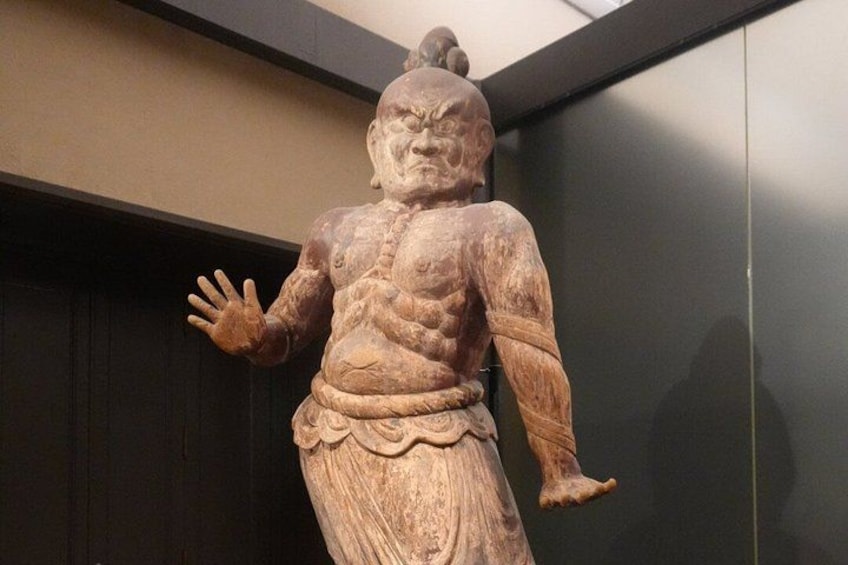 A terracotta statue with a muscular build, raised arms, and a detailed skirt. 4
