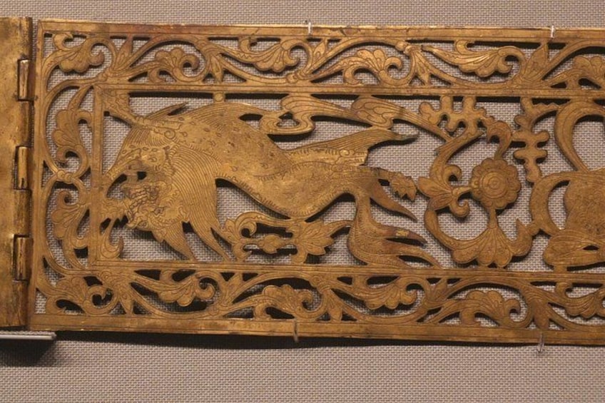 A detailed wooden panel with intricate carvings of a mythical creature and floral patterns. 5