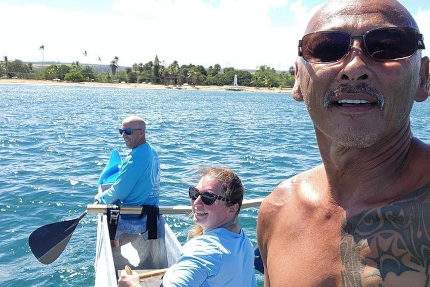 A person in a boat on a body of water with a beach and palm trees in the background. 1