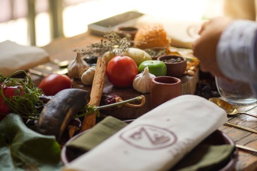 Une table en bois sur laquelle on trouve divers aliments, notamment des tomates, de l’ail et des herbes aromatiques. 1