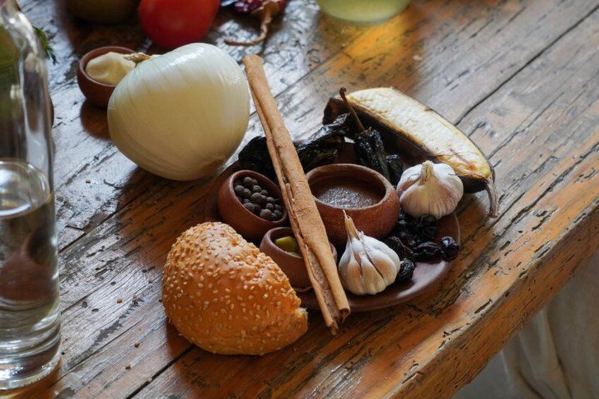 Une table en bois avec un hamburger, de l’ail, des épices et une bouteille d’eau. 5