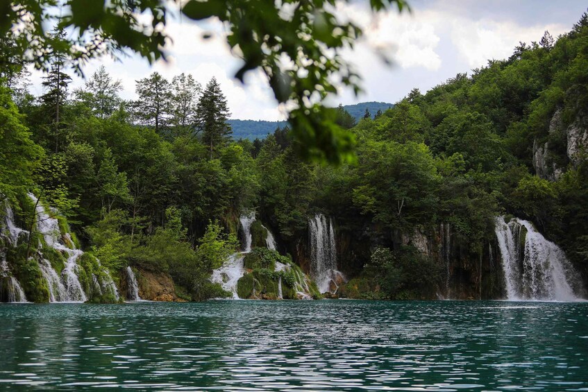 Ein Wasserfall stürzt in einen See, umgeben von dichtem Wald und felsigen Klippen. 5