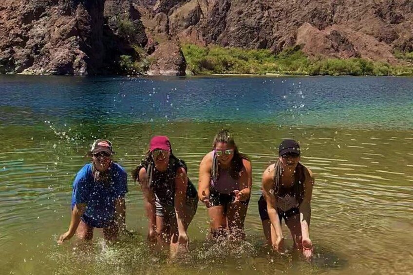 Four people in a shallow lake surrounded by rocky terrain. 1