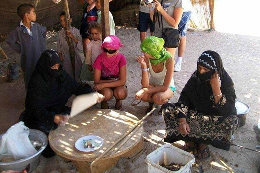 Een groep mensen zit buiten aan een tafel en is bezig met documenten en een schaal. 3