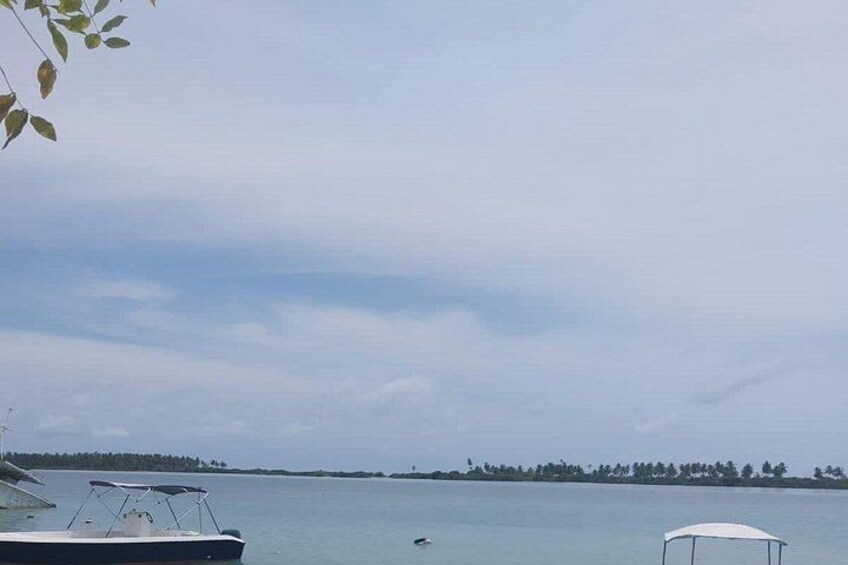 A calm lake with boats, a distant shoreline, and a clear sky. 2