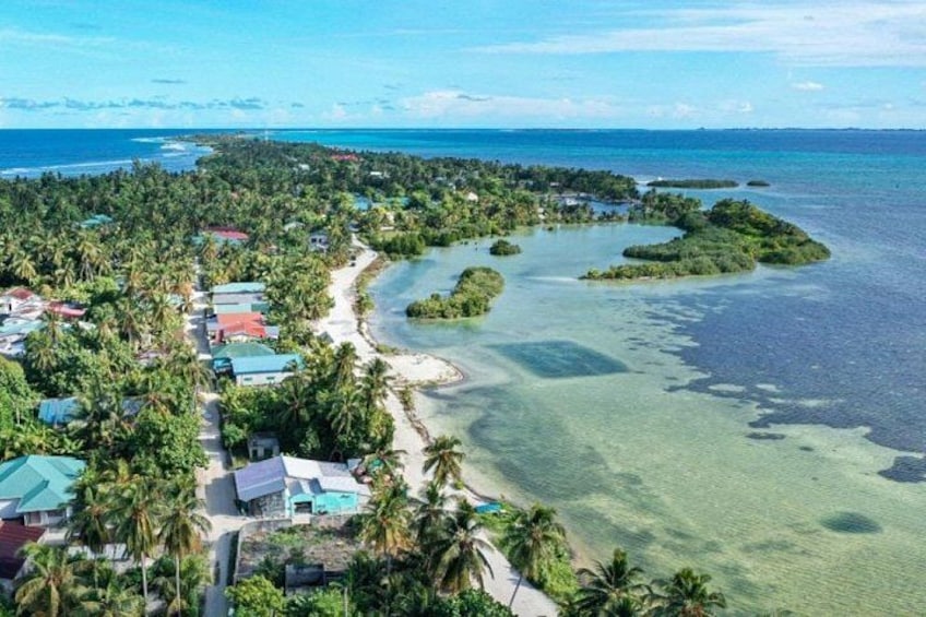 A coastal village with houses, a beach, and a clear blue sea. 1