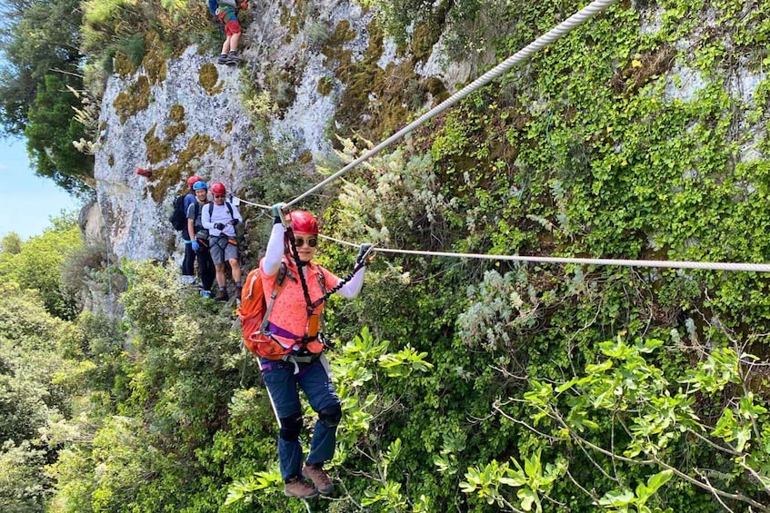 Una persona haciendo rappel por un risco rocoso con vegetación. 4