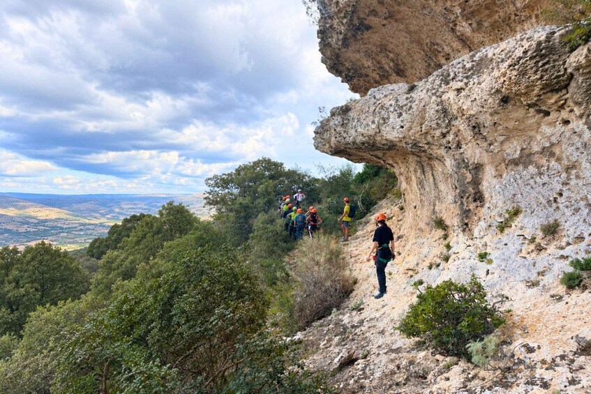Un grupo de excursionistas en un sendero rocoso con vistas al paisaje y colinas distantes. 2