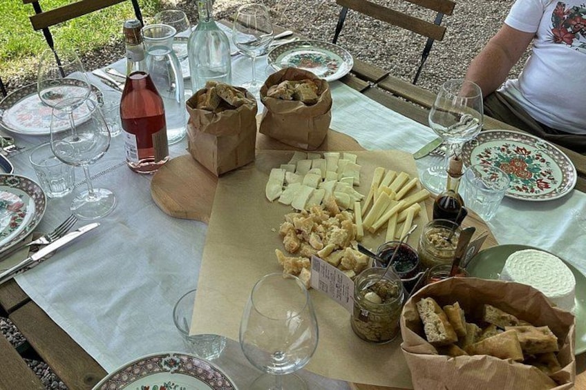 Et udendørs spisebord med tallerkener, bestik, vinglas og mad. 5