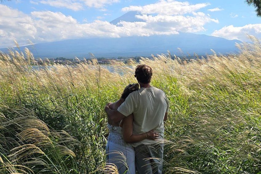 Two people embracing in a field with tall grass and a mountain in the background. 1