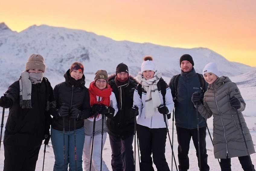 A group of people with skis standing on snow-covered ground with mountains in the background. 4