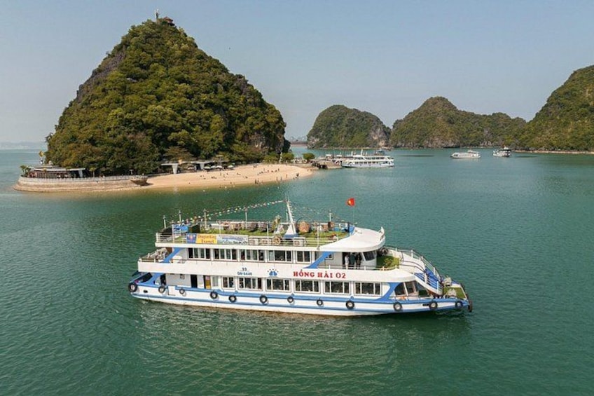 A large boat named 'HÀNG HÀI 02' on calm waters with a small island in the background. 2