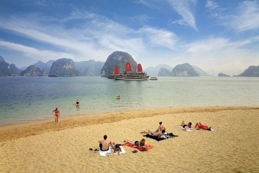 A beach with people sunbathing and swimming, a boat with red sails, and a mountainous landscape in the background. 2