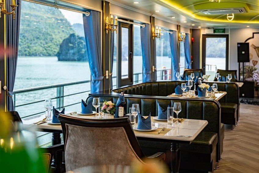 A restaurant with tables set for dining, large windows overlooking a body of water, and a view of a mountainous landscape. 2