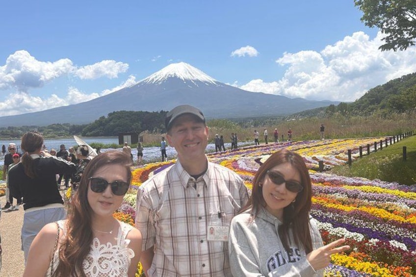 A group of people at a flower field with a mountain in the background. 1