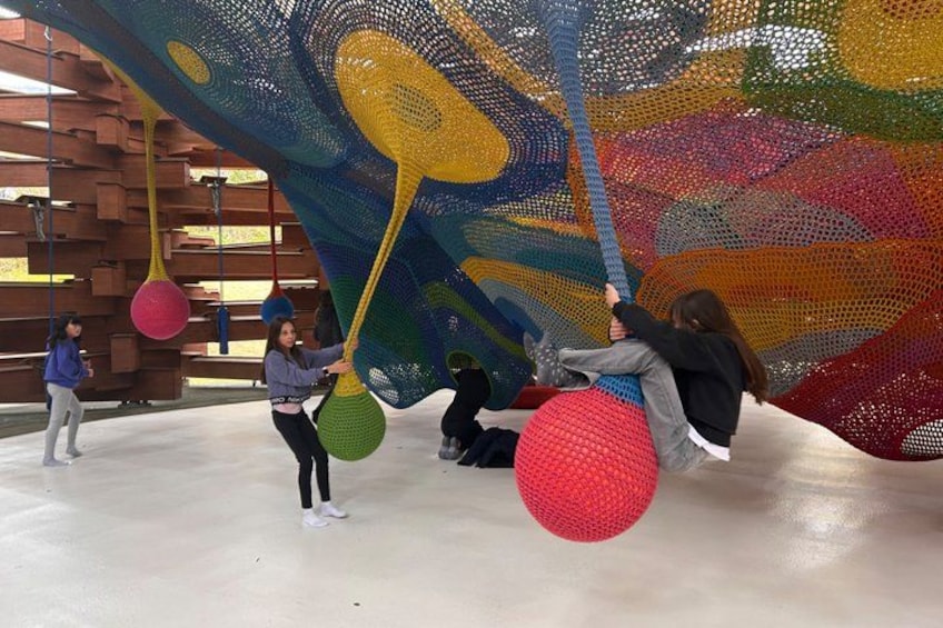A group of people interacting with colorful, net-like structures in an indoor setting. 3
