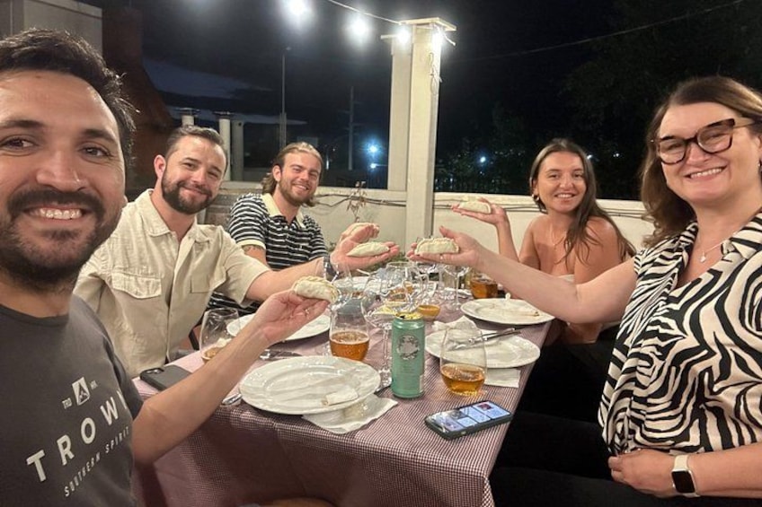 Eine Gruppe von Menschen speist abends draußen an einem gedeckten Tisch. 2