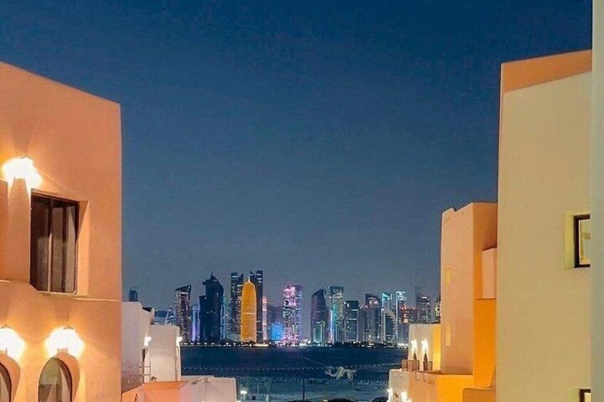 Un horizonte urbano nocturno con edificios iluminados y un puente en primer plano. 3