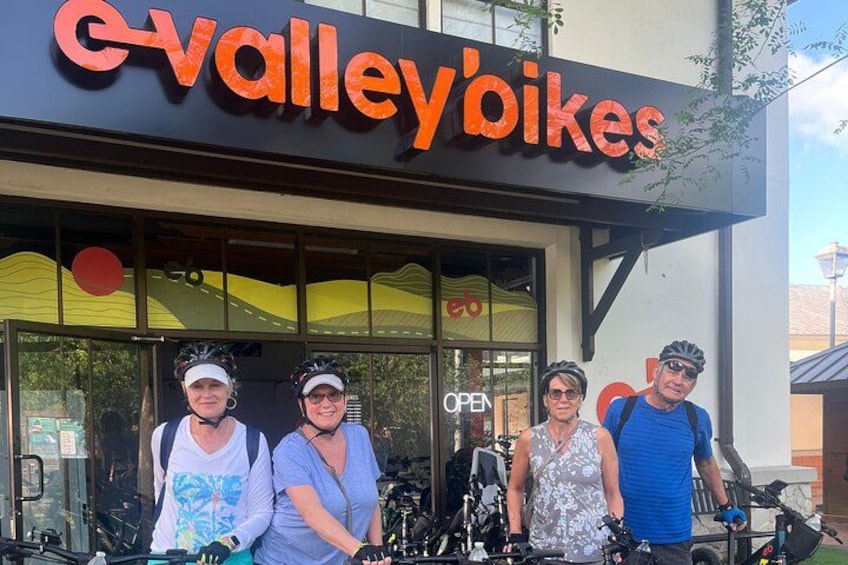 A storefront with a sign reading 'eValley'Bikes' and a group of people standing in front of it. 4