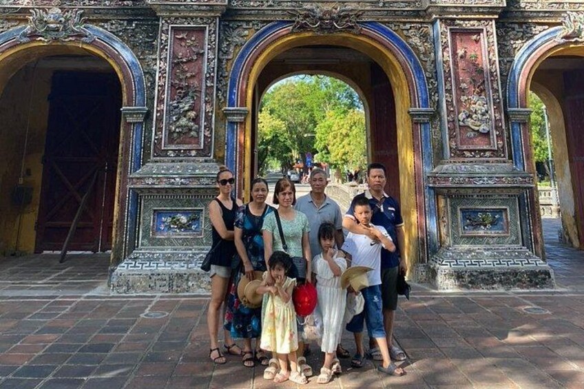 A group of people standing in front of a historic gate with intricate carvings and a large archway. 2