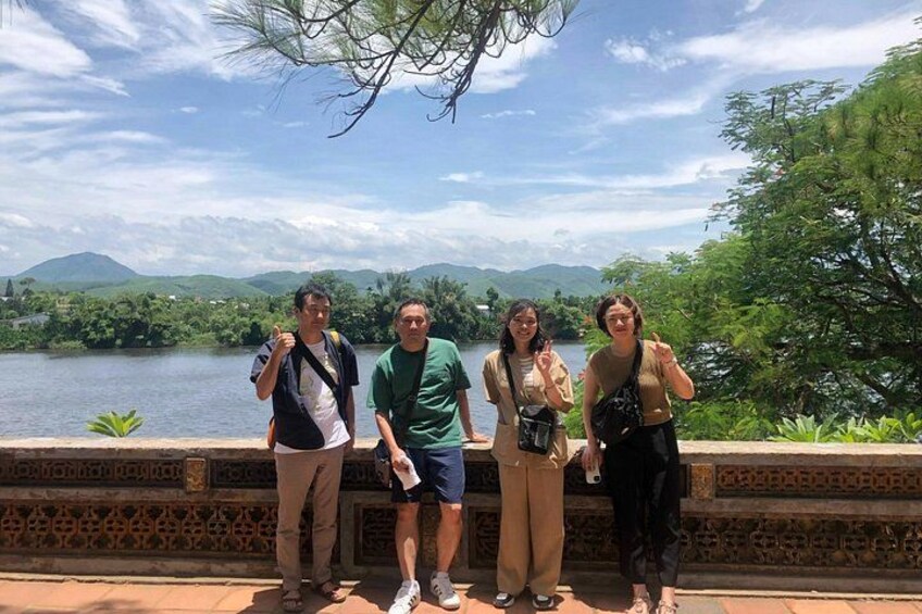 Four people standing by a river with mountains in the background. 5