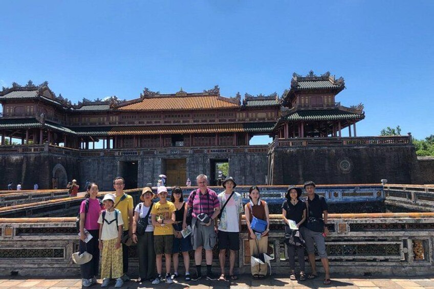 A group of people standing in front of a traditional Chinese building with a tiled roof and ornate architecture. 4