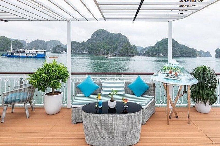 A deck with outdoor furniture, potted plants, and a view of a body of water with boats. 4