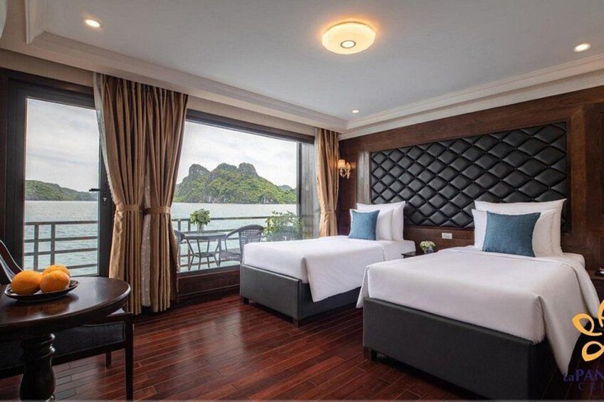 A hotel room with two beds, a view of a body of water, and a dining area with a table and chairs. 1