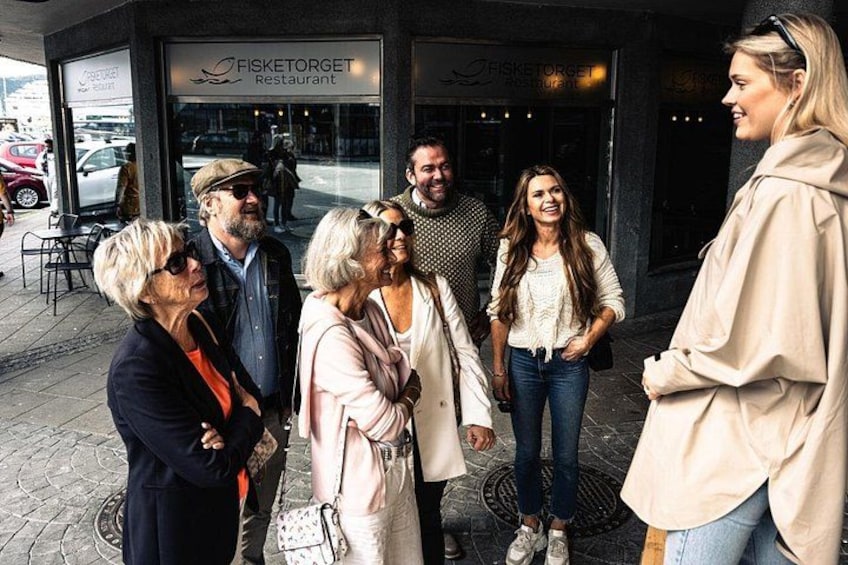 A group of people standing outside a restaurant named FISKETORGET. 2