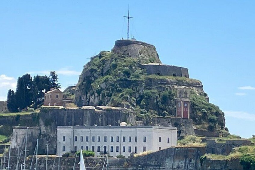 A fortified hilltop with a cross, a building with multiple windows, and a red door. 3