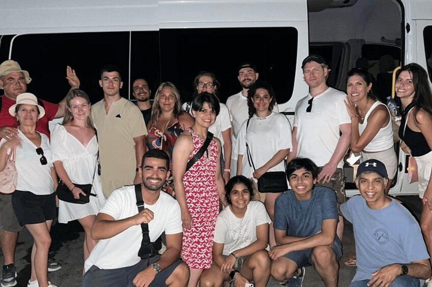 A group of people posing in front of a white vehicle. 3