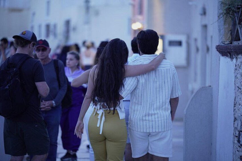 A group of people walking down a narrow street. 2