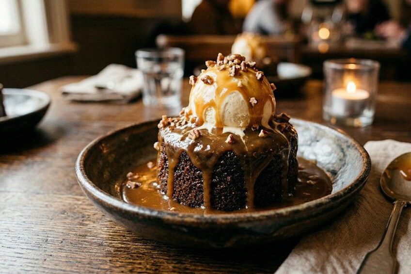 A dessert on a plate with caramel sauce and nuts. 1