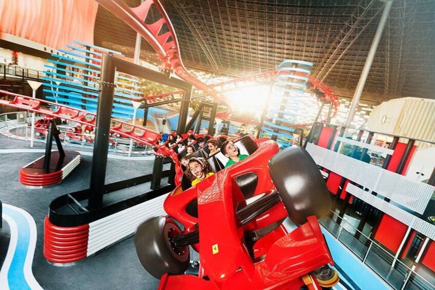 Una montaña rusa con coches rojos en un parque de atracciones cubierto. 4