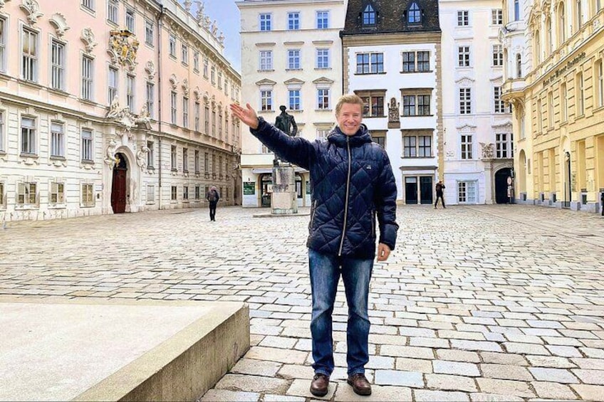 A person standing in a cobblestone square with historic buildings in the background. 1