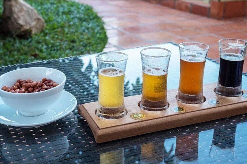 Un plateau avec quatre verres de bière et un bol de cacahuètes, posé sur une table. 4