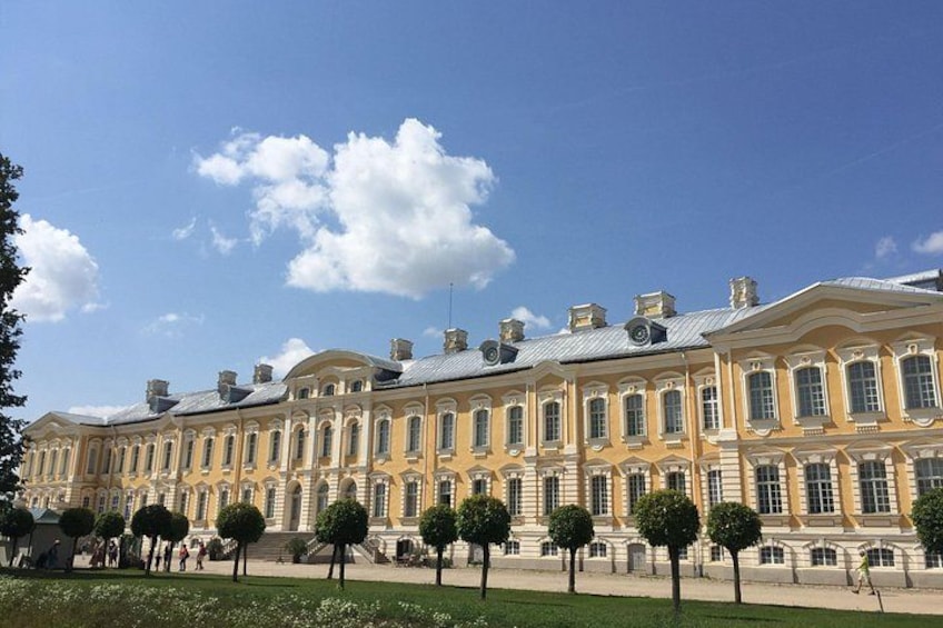 A large classical building with symmetrical architecture, a clear blue sky, and a well-maintained lawn with trees. 4