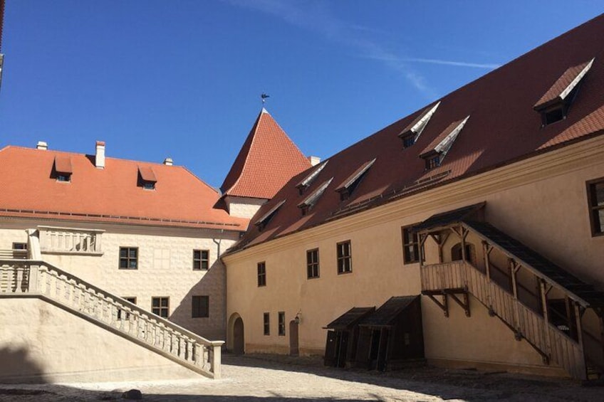 A historic building with a red roof, a staircase, and a small balcony. 3