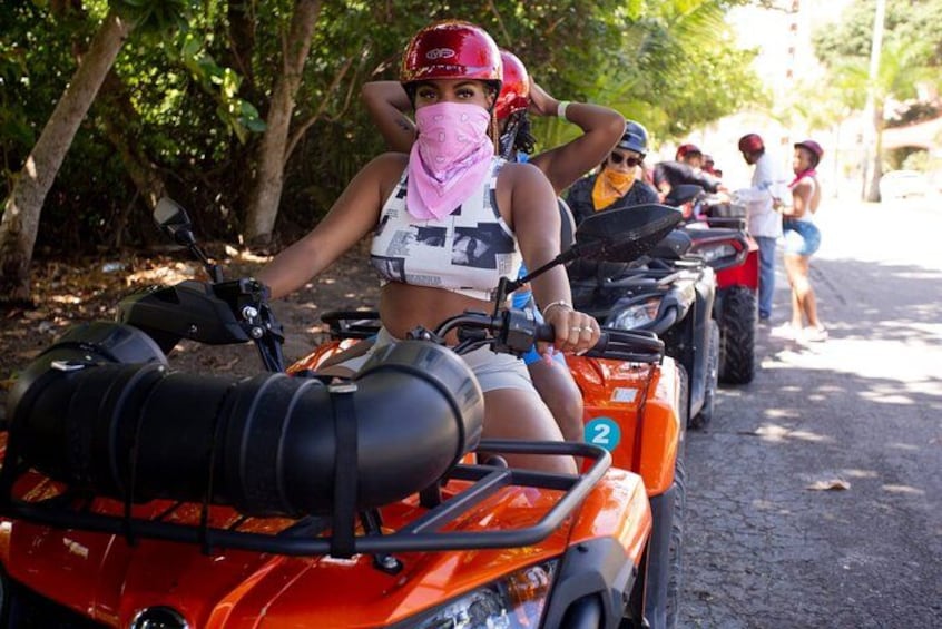 People riding ATVs on a dirt road surrounded by trees. 1