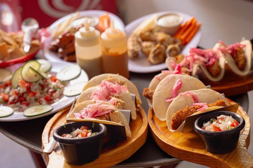 Ett urval av tacos och tillbehör serverade på träbrickor, inklusive strimlat kött, inlagda grönsaker och en liten skål med salsa. 5
