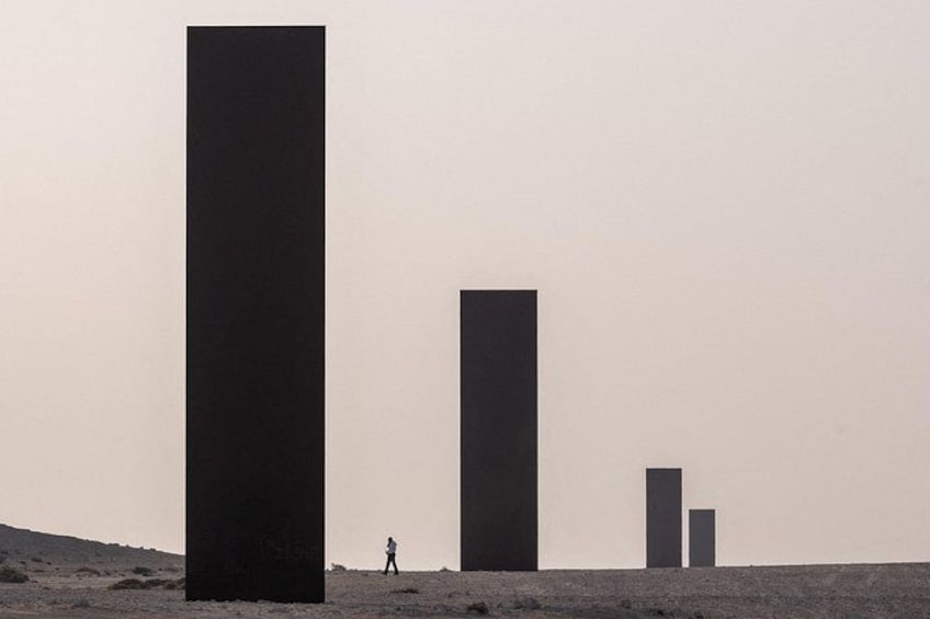 A desert landscape with three large, dark rectangular structures. 1